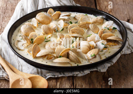 Leckere Muscheln in einer cremigen Sauce mit Knoblauch und grünen Nahaufnahme auf einem Teller auf den Tisch. horizontale Stockfoto