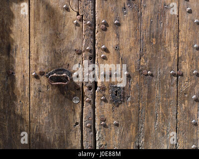 Alte Holztür in Cadaques. Detail einer naturbelassenes Holztür mit alten rostigen Schleuse, Griff und eine neuere Sperre. Nieten Punktion die Oberfläche. Stockfoto