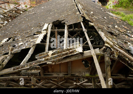 Beschädigte Asbest Welldach auf alten verlassenen Industriegebäude. Stockfoto