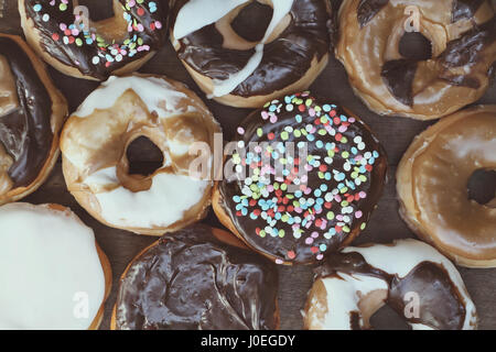 Verschiedene frische Donuts über rustikale Hintergrund. Bild von oben. Stockfoto