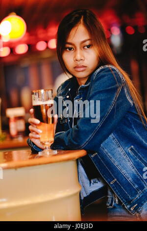 Junge schöne Frau trinkt Bier in einer bar Stockfoto