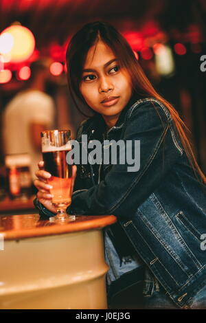 Junge schöne Frau trinkt Bier in einer bar Stockfoto