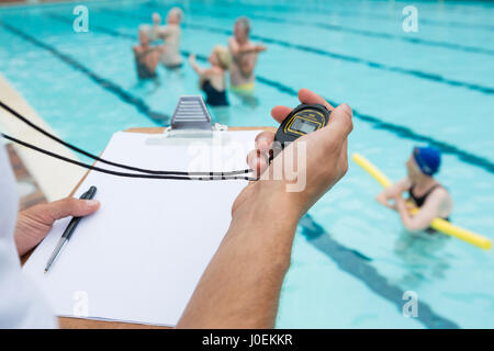 Schwimmen Sie Trainer betrachten Stoppuhr nahe am Pool in der Freizeit-Mitte Stockfoto