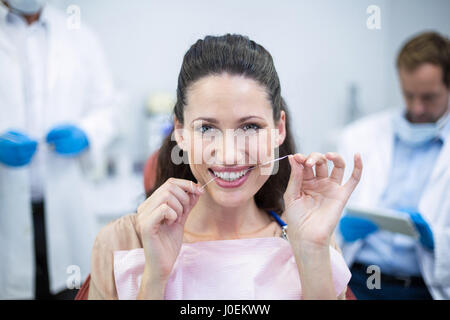 Patientin, die Zahnseide ihre Zähne dental clinic Stockfoto