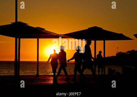 Passanten, die bei Sonnenaufgang in Copacabana Strand Rio De Janeiro, Brasilien Stockfoto