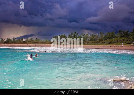 Surfer warten auf Wellen wie ein Sturm nähert sich ein beliebter Surfstrand in Jupiter, Florida. Stockfoto
