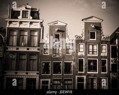 Traditionelle Häuser reflektieren den Charme eines Kanals in Amsterdam während des späten Nachmittagslichts. Niederlande Stockfoto