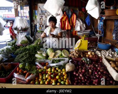 CAINTA, RIZAL, Philippinen - 21. Dezember 2016: Ein Markt Anbieter im Inneren einen Obst und Gemüse Stall auf einem öffentlichen Markt. Stockfoto