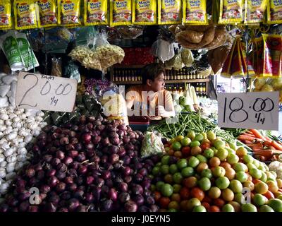 CAINTA, RIZAL, Philippinen - 21. Dezember 2016: Ein Markt Anbieter im Inneren einen Obst und Gemüse Stall auf einem öffentlichen Markt. Stockfoto