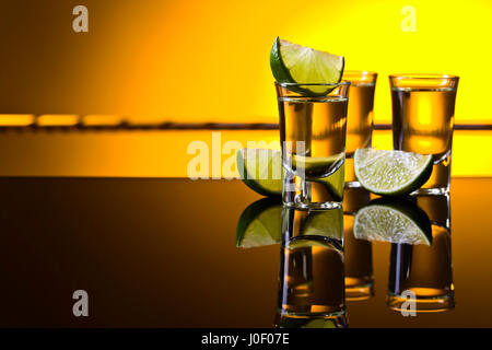 Mexikanische Gold Tequila lime Kurzum Gläser mit auf reflektierenden Hintergrund. Exemplar. Stockfoto