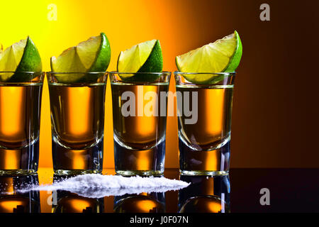 Mexikanische Gold Tequila in Kurze Scheiben mit Kalk und Salz auf reflektierenden Hintergrund. Stockfoto