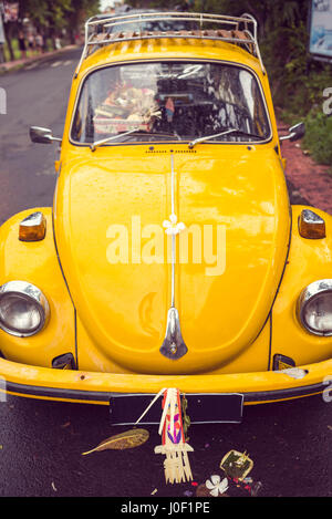 Flower-Power - Blume auf einer Motorhaube eines gelben Vintage 70er Jahre Hippie-Autos. Hippie Retro-Stil Bug oder Käfer restauriert Auto. Stockfoto