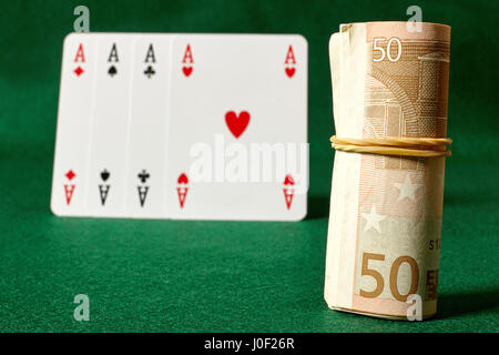 Rolle des Geldes und vier Asse auf grünen table.Ιllegal Glücksspiel. Stockfoto