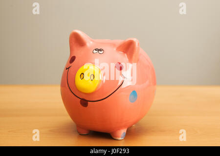 Rosa Sparschwein auf Holztisch. Stockfoto