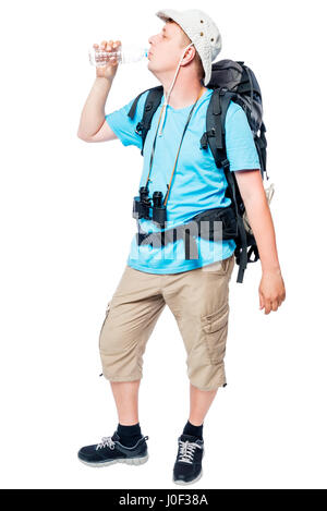 Wanderer mit einem Rucksack trinkt eifrig Wasser aus einer Flasche auf weißem Hintergrund Stockfoto