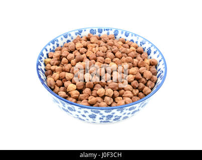 Schwarze Kichererbsen in einer blau-weißen Porzellanschüssel mit floralem Design, isoliert auf weißem Hintergrund Stockfoto