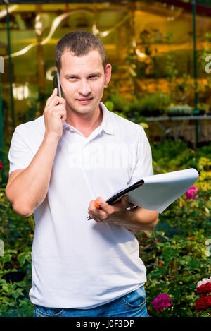 Porträt eines Unternehmers mit einem Handy in einem Gewächshaus Stockfoto