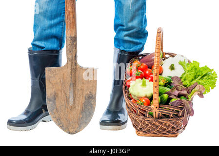 Füße eines Bauern in Gummistiefeln und ein Korb mit Gemüse auf einen weißen Hintergrund-Nahaufnahme Stockfoto