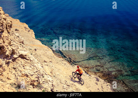 Mountainbiker am Fahrrad im Sommer inspirierende Berge und Meer Landschaft reiten. Mann Radsport MTB auf der Enduro Trail Strecke am Meer und felsigen Schmutz pat Stockfoto