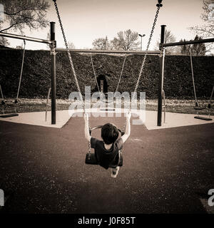Junge auf einer Schaukel auf einem französischen Park Spielplatz Stockfoto