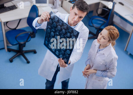 Schöner angenehmer Arzt mit seinem Kollegen eine X-Ray Foto Stockfoto