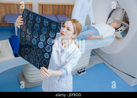 Schöne weibliche Radiologe Blick auf die MRI Scan-Bilder Stockfoto
