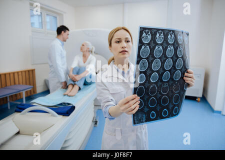 Medizinische Diagnose. Ernst schön junge Onkologen hält das Ergebnis der CT scannen, und untersuchen sie beim Einsetzen einer Diagnosis für ihre Patienten Stockfoto