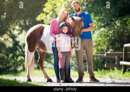 Islandpferd. Paar mit Mädchen stehen neben Skewbal Pferd. Österreich Stockfoto