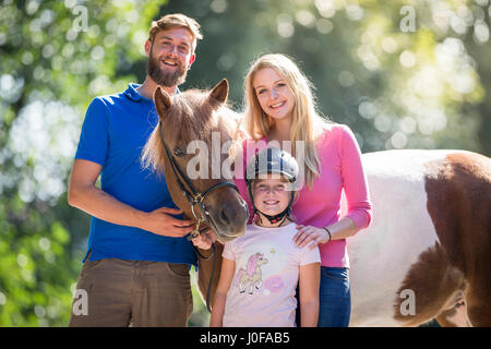 Islandpferd. Paar mit Mädchen stehen neben Skewbal Pferd. Österreich Stockfoto