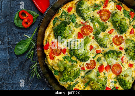 Frittata mit Brokkoli, Spinat, Paprika und Tomaten in Eisen Pfanne. Art der italienische Omelett mit Gemüse. Stockfoto