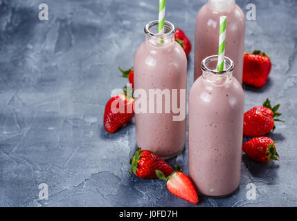 Erdbeer-Banane Smoothie in drei Flaschen auf blauem Hintergrund Stockfoto