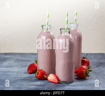 Erdbeer-Banane Smoothie in drei Flaschen auf blauem Hintergrund Stockfoto