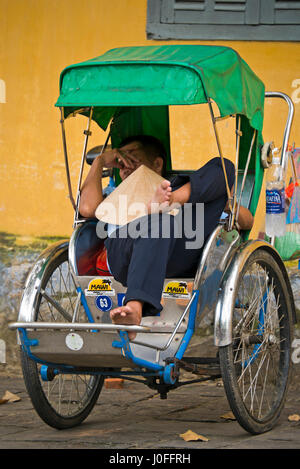 Vertikale Ansicht von einem Cyclo-Fahrer entspannend in Hoi an, Vietnam. Stockfoto