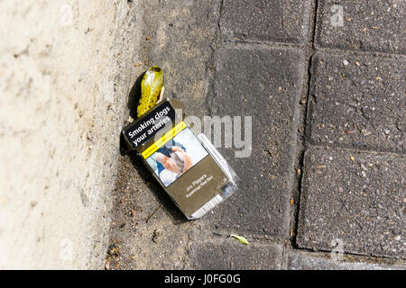 Rauchen verstopft Ihre Arterien Warnhinweis auf eine leere weggeworfene Zigarettenschachtel JPS Players. Stockfoto