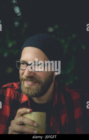 Authentische Porträt einer stattlichen und happy Hippie Mann sitzt auf der Veranda Kaffee zu trinken. Stockfoto