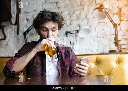 gut aussehender Mann trinken aus einem Becher Bier in einer bar Stockfoto