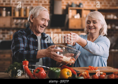 Porträt des Lächelns älteres paar machen Salat zusammen in Küche Stockfoto