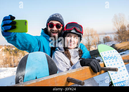 Junger Mann und Frau umarmen und nehmen Selfie mit snowboards Stockfoto