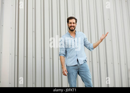 lächelnd jungen männlicheren Mann in Jeans zeigt eine leere Seite des Bildes Stockfoto