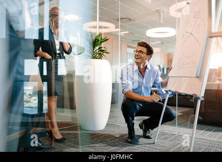 Glücklich Reife kaukasischen Geschäftsmann in der Nähe von flip Board mit Diagramm. Büroangestellte hält einen Vortrag auf einem Flipchart an Kollegen und lächelnd. Stockfoto