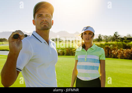 Junge Golfer am Golfplatz zusammen. Männlichen und weiblichen Golfspieler auf Feld an einem sonnigen Tag. Stockfoto