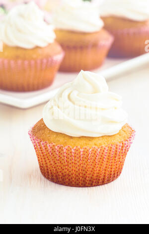 Gourmet-Cupcakes mit weißer Buttercreme Zuckerguss auf weißer Holztisch Stockfoto
