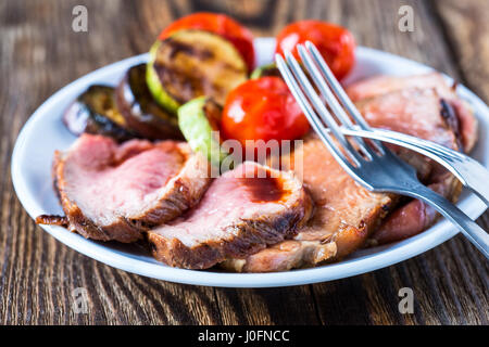 In Scheiben braten selten Lendenbraten mit gebratenem Gemüse auf rustikalen hölzernen Hintergrund Stockfoto