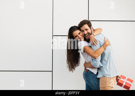 schöne junge Frau umarmt ihren Geliebten mit einem Überraschungs-Geschenk für Sie Stockfoto