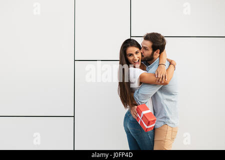 schöne junge Frau umarmt ihren Geliebten mit einem Überraschungs-Geschenk für Sie Stockfoto