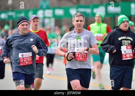 Männer, die unter einem Meer von Läufern, wie sie Ansatz, der die Ziellinie am Shamrock Shuffle Rennen in Chicago, Illinois, USA 2017. Stockfoto