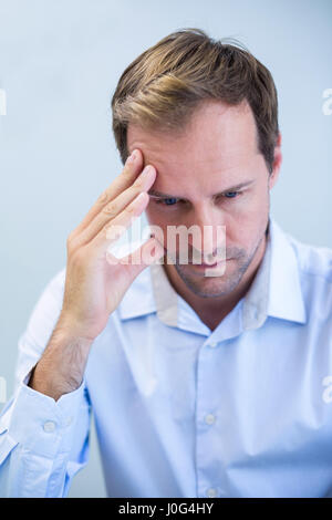 Nahaufnahme des gespannten Zahnarzt sitzend mit Hand auf Stirn in Klinik Stockfoto