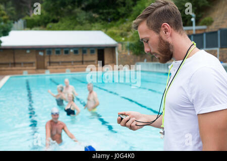 Schwimmen Sie Trainer betrachten Stoppuhr nahe am Pool in der Freizeit-Mitte Stockfoto