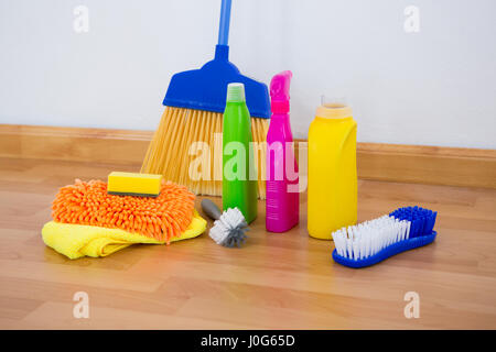 Chemischen Flaschen mit Pinsel und Schwämme mit Besen am Boden gegen die Wand Stockfoto