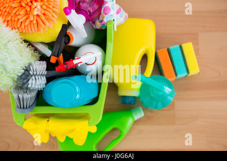 Draufsicht der Sprühflaschen und Reinigungsgeräte in Eimer auf Parkett Stockfoto